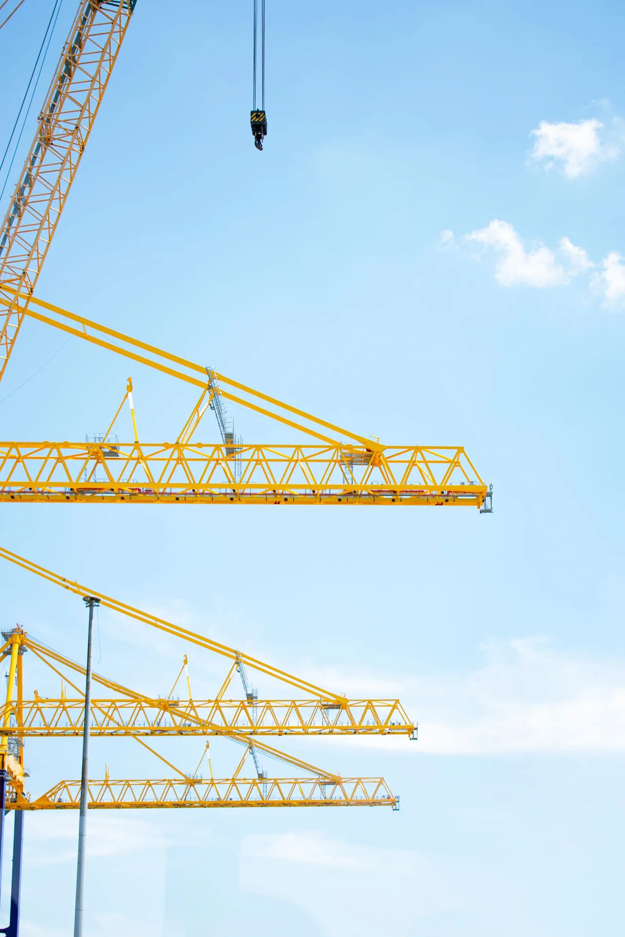 Tower crane jibs reaching across a clear sky above a construction site