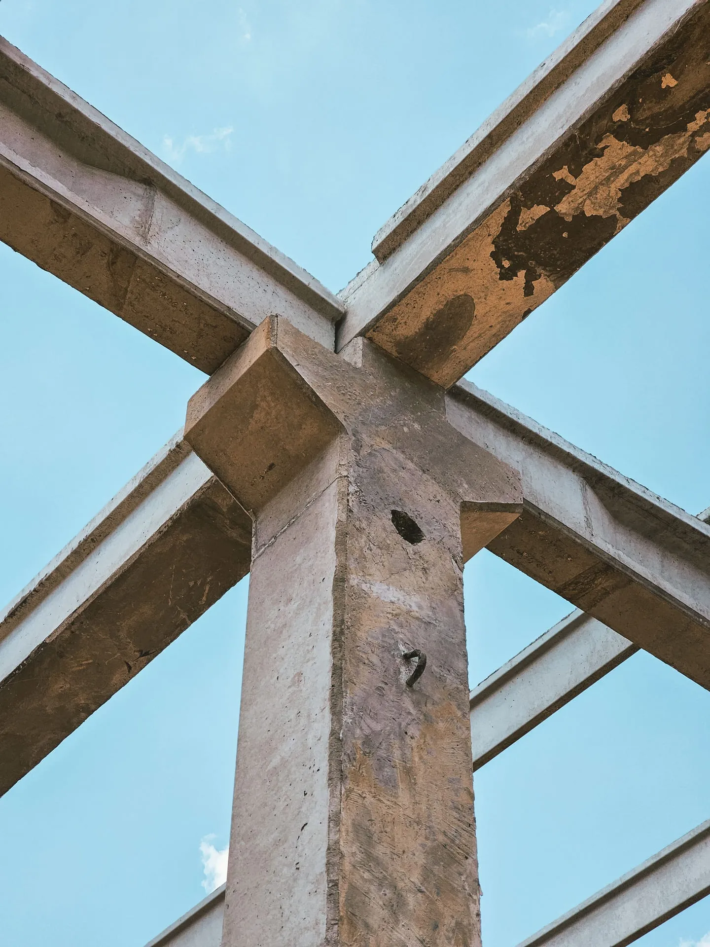 Upward view of a concrete frame under construction against a clear sky