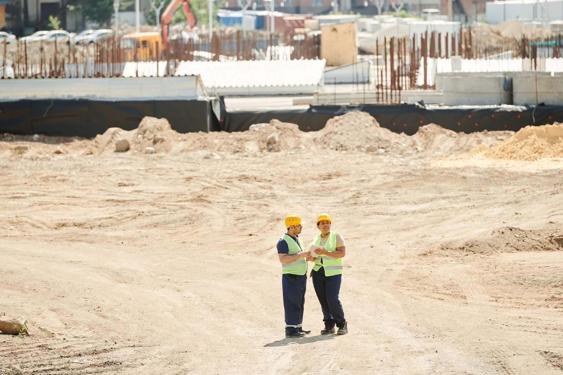 Two workers in hard hats reviewing plans together on a construction site