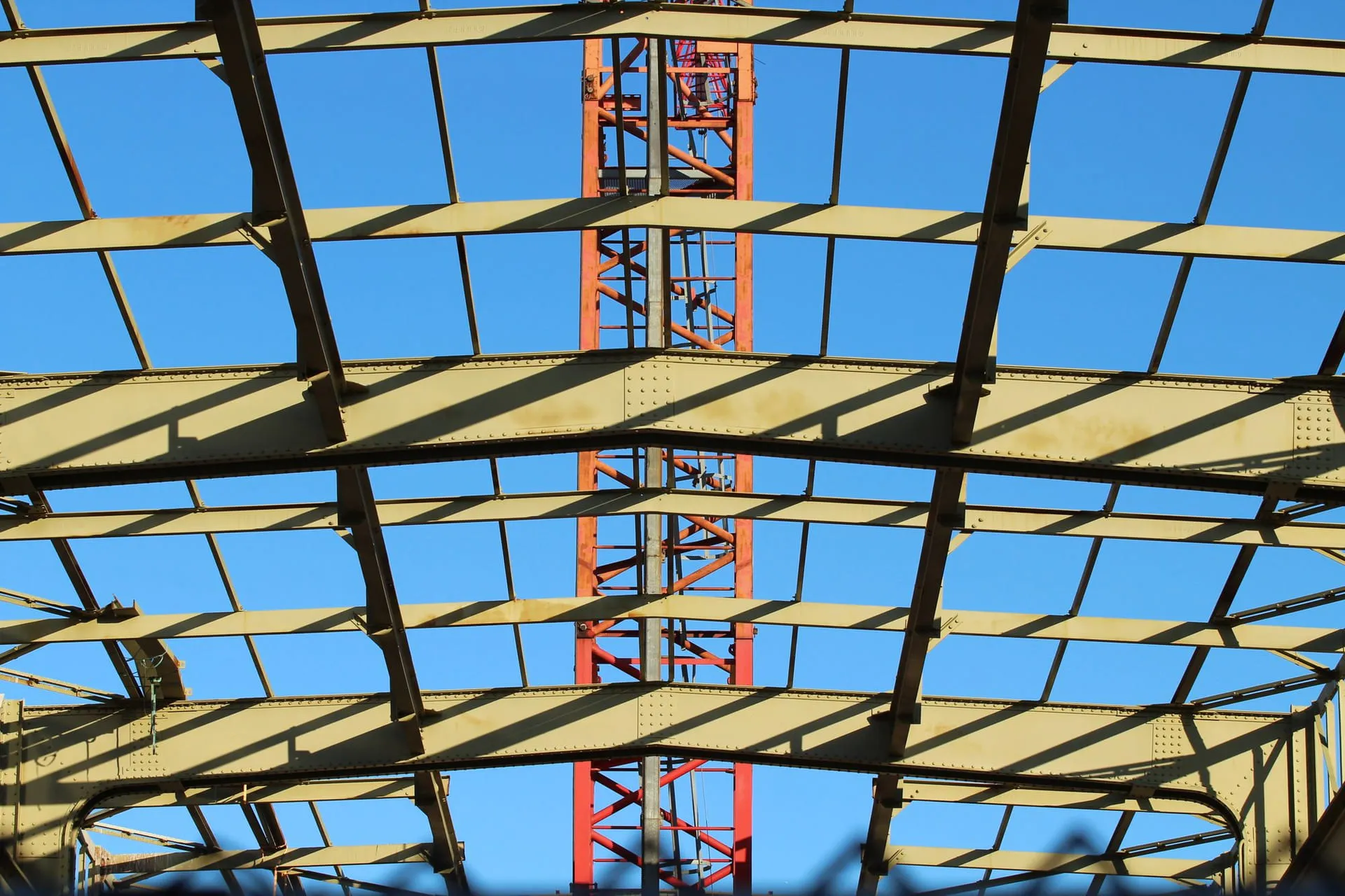 Structural steel framework rising under a clear blue sky