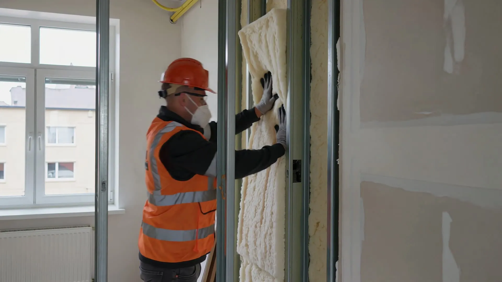Installer fitting insulation between studs ahead of drywall